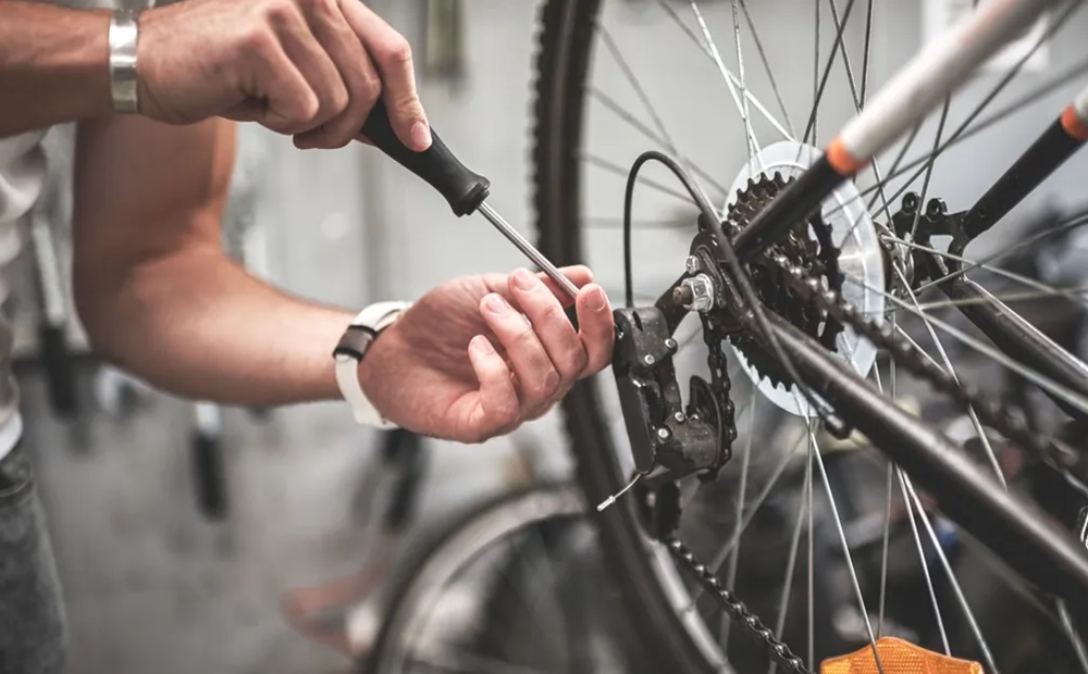 Closeup of a man's hands fixing a bike's gears.